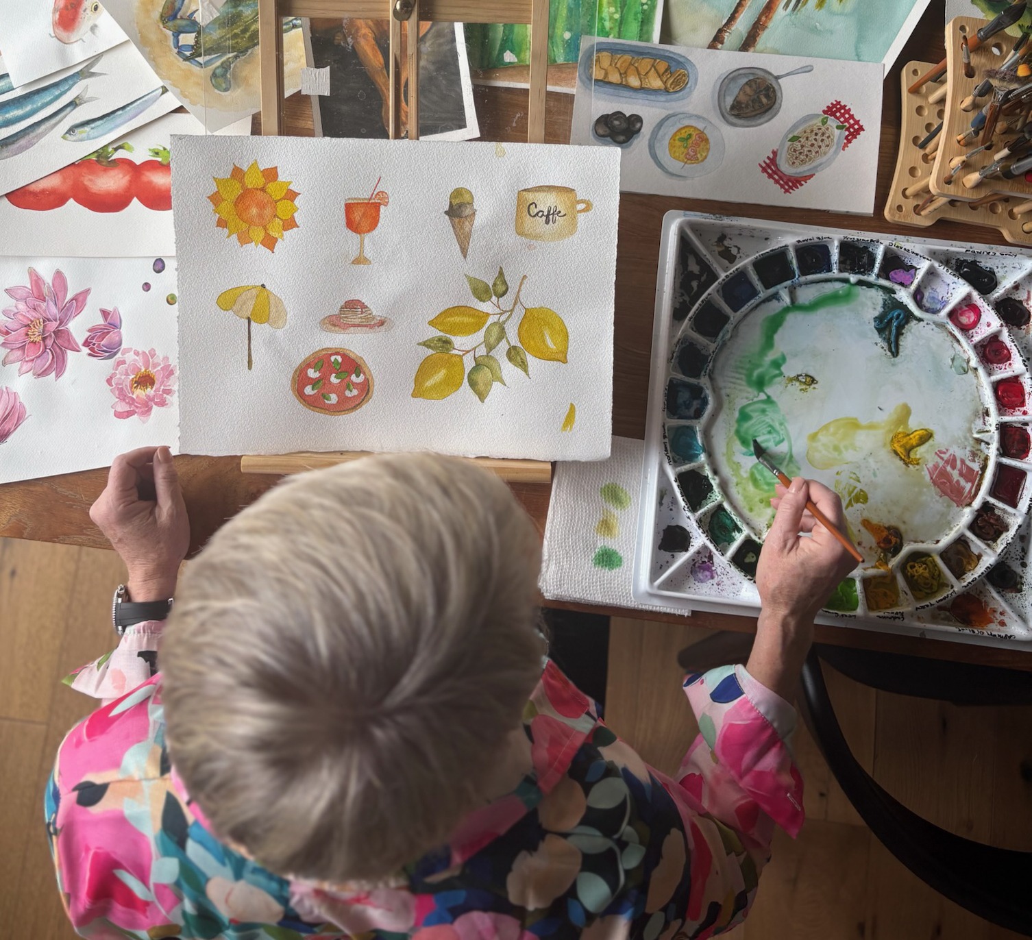 Mary Beth Cadwell painting in her Floxie studio, surrounded by watercolor works in progress